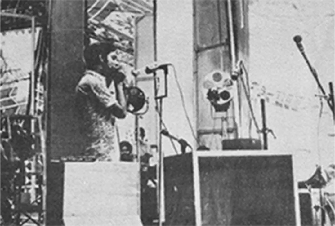 A singer at the microphone between speaker stacks