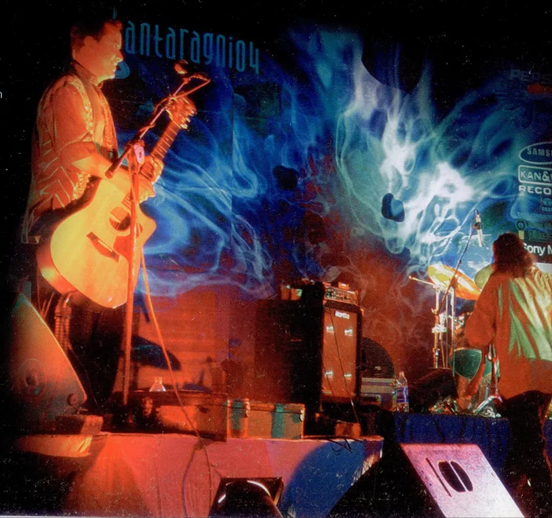 A guitarist sings in front of a blue fire banner reading antaragni04