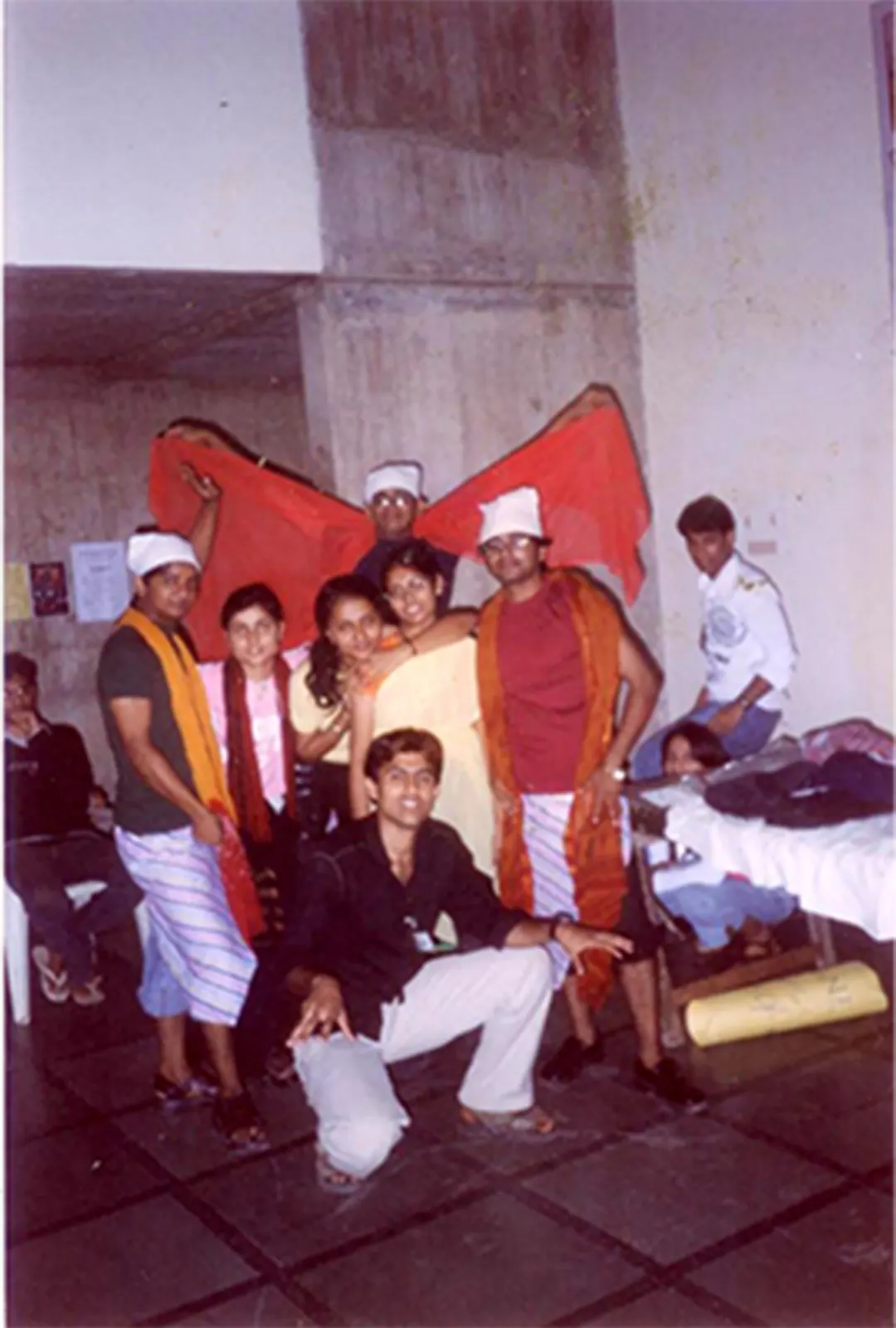 A cast in costume crowds in front of a painted backdrop