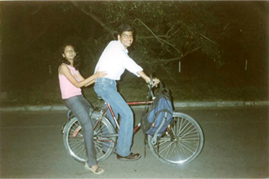 Two people on one bicycle on a campus road at night