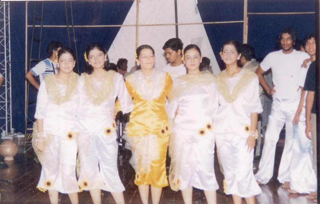 A dance troupe in white and gold, posing together on stage