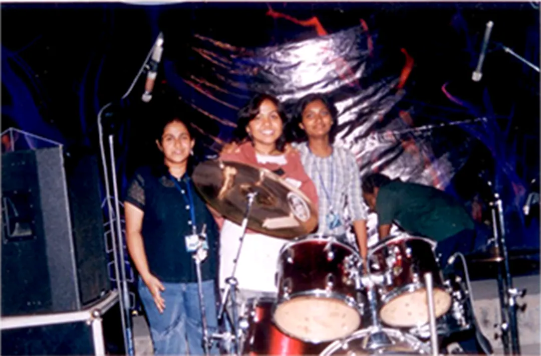 Three musicians around a red drum kit